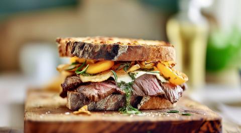 Nichts geht über ein gutes Sandwich. Saftiges Fleisch, süße Aprikosen und geschmolzener Käse treffen auf knusprig geröstetes Sauerteigbrot. Die frische Kräutersauce und ein paar Kartoffelchips machen es perfekt.